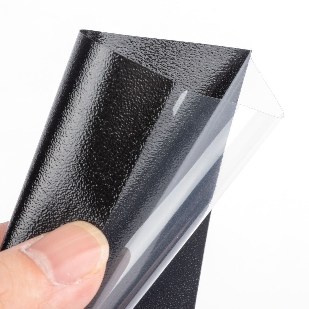 Hand holding a black deck protector with a clear plastic surface