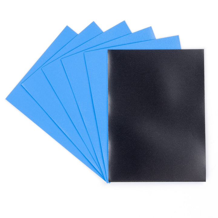 Five blue and one black deck protector sleeves on a white background