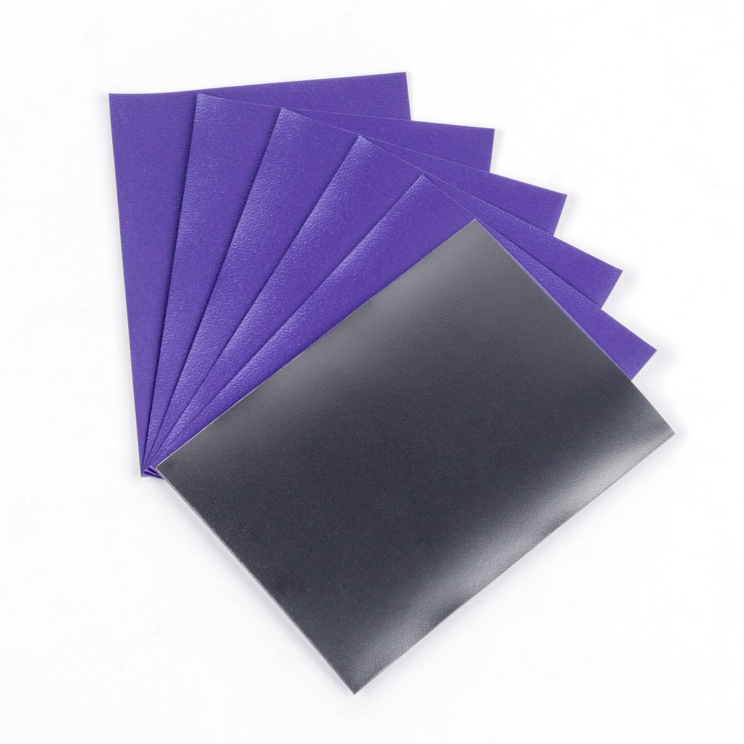Five purple and one black matte deck protector sleeves on a white background