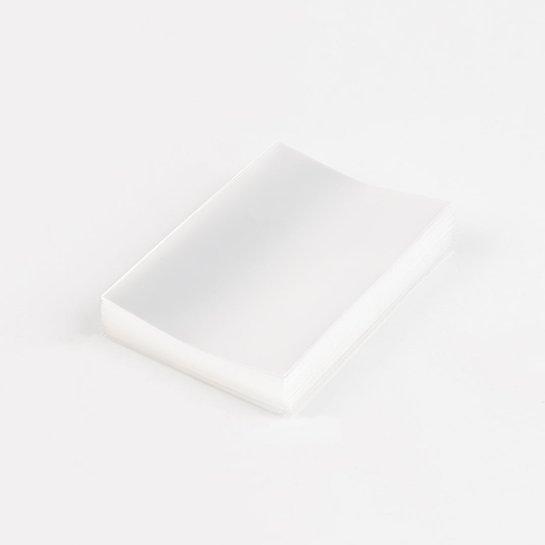 A stack of transparent card sleeves on a white table.