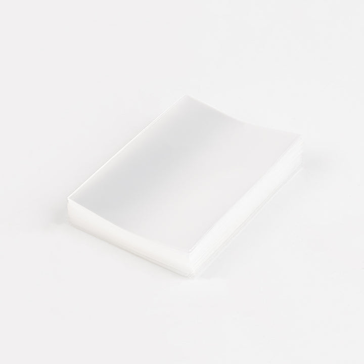 A stack of transparent card sleeves on a white table.