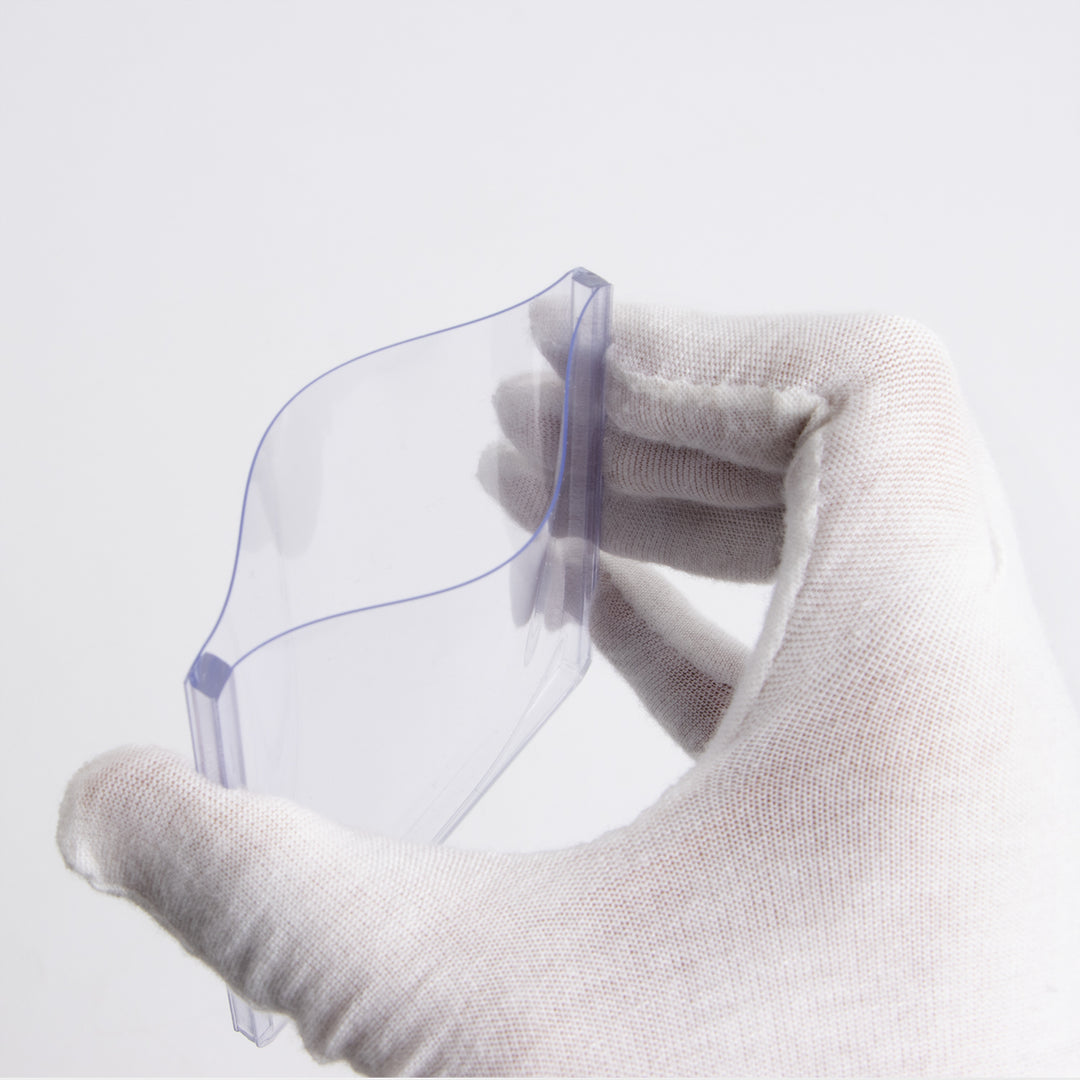 Gloved hand squeezing a 130 point toploader against a white background.