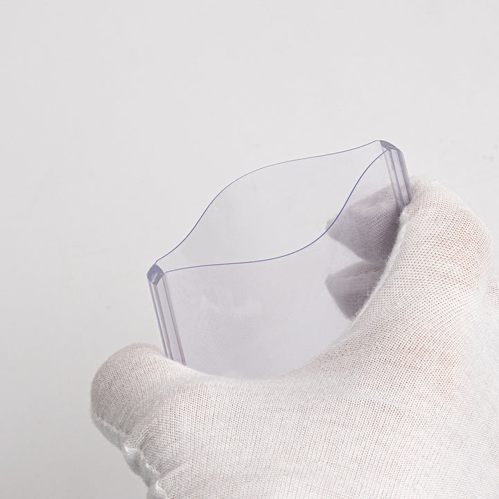 A gloved hand squeezing a 180 point toploader against a white background.