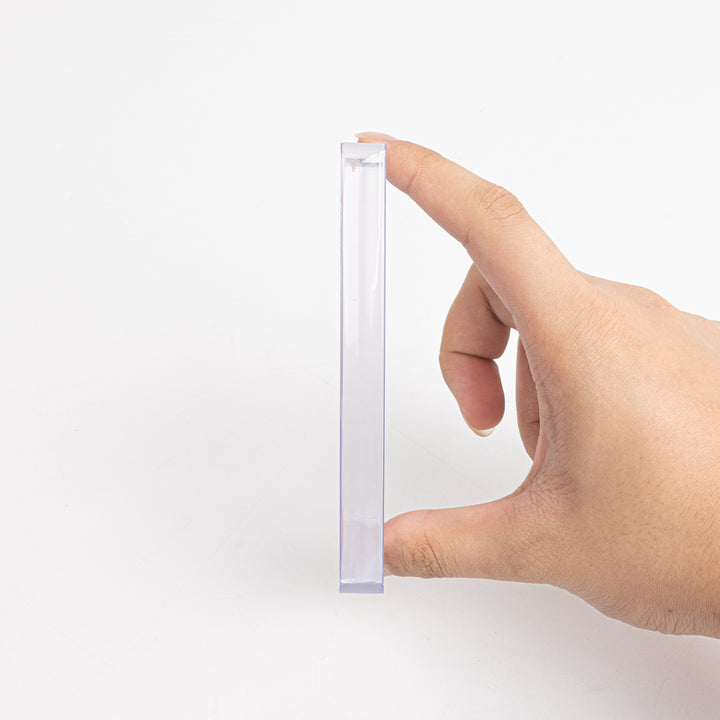A sideview of a 360 point toploader being held between a thumb and a finger.