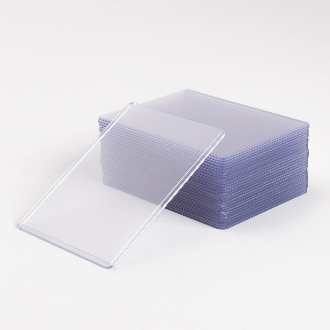 A stack of 55 point toploaders, with a single toploader leaning at a 45 degree angle against it, with a white background.