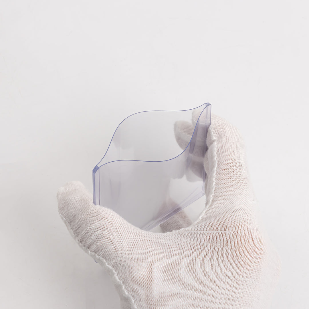 A white gloved hand squeezing a 55 point toploader, against a white background.